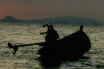 Romantische Stimmung beim Sonnenuntergang in Thailand, ein Longtailboot vor Anker.