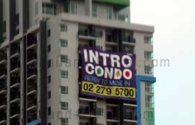 Wohnungen in Thailand zu vermieten steht auf dem Werbeplakat an der Fassade von dem Hochhaus in Bangkok, Intro Condo und die Telefonnummer 02 279 5700.